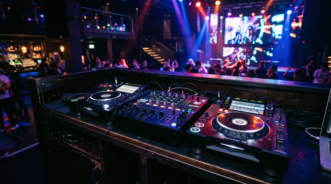 Two standalone CDJ media players either side of a club mixer in a dark booth
