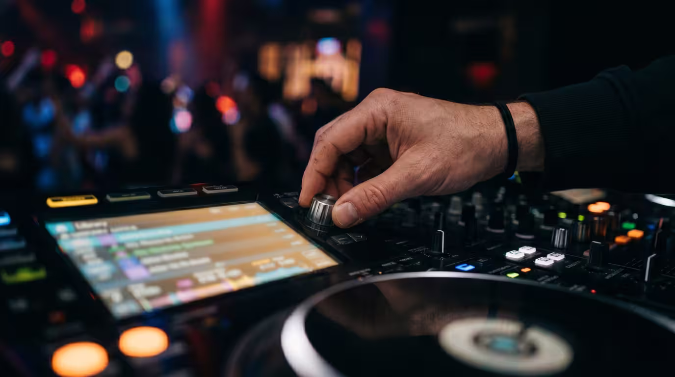 A DJ browsing tracks on a controller's library screen in a booth